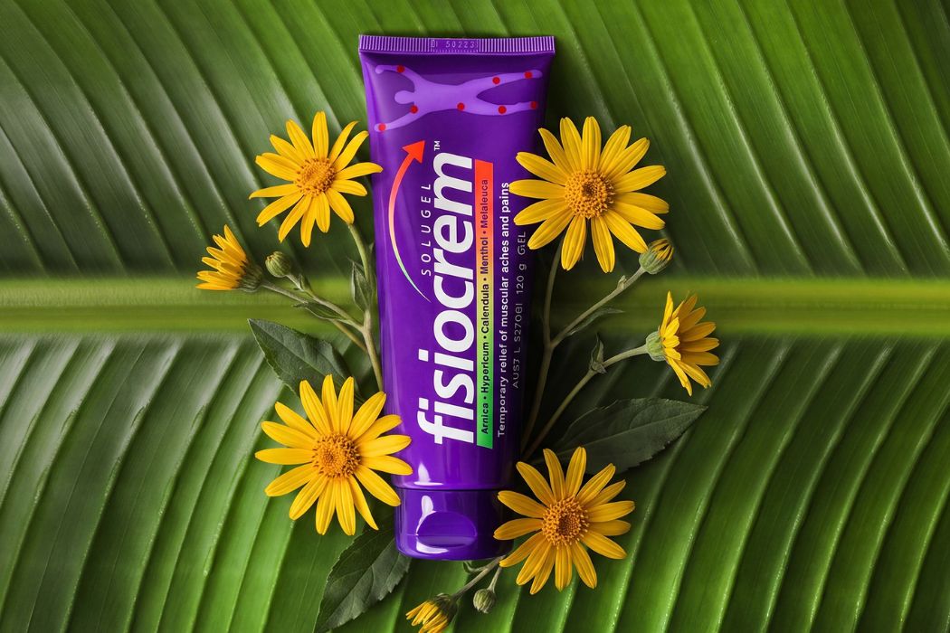 fisiocrem Solugel muscle pain relief cream 120g tube surrounded by yellow flowers on a large green leaf.