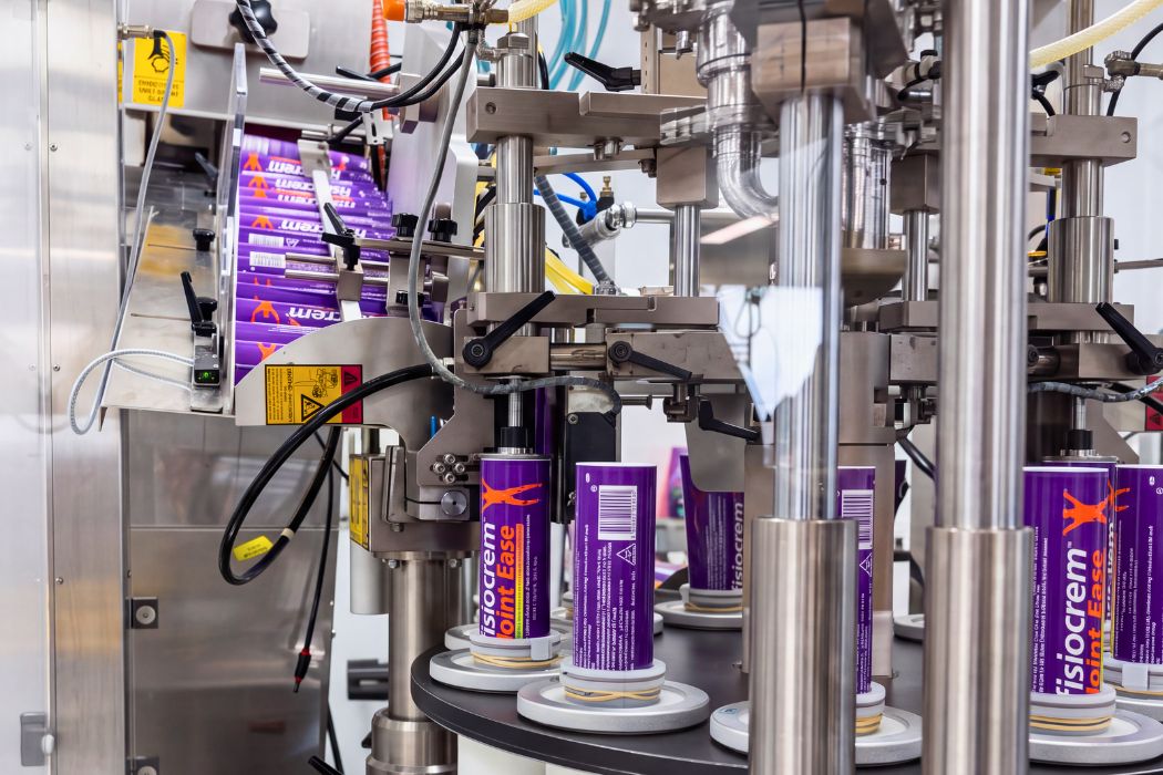 fisiocrem Joint Ease joint pain relief cream tubes moving through a manufacturing machine.