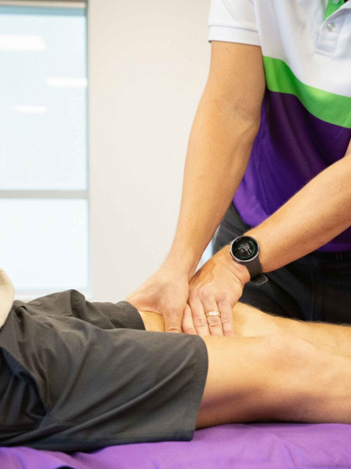 Practitioner massaging a client's thigh on a treatment table.