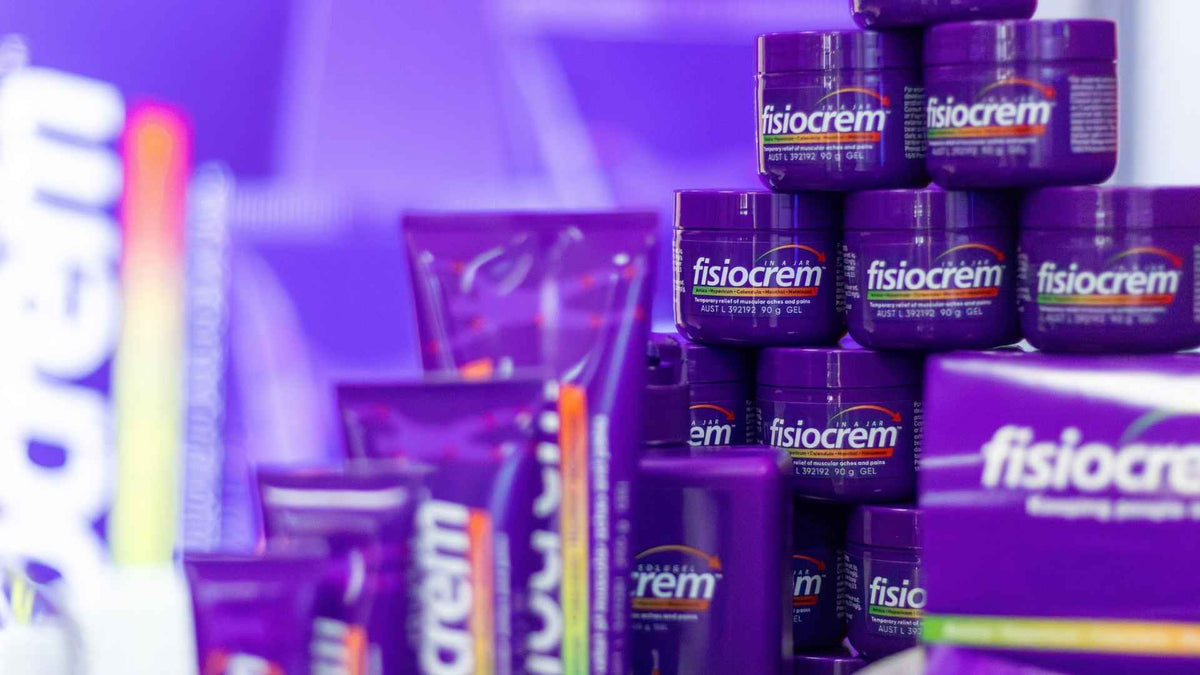 Stacks of purple fisiocrem tubs and tubes on an exhibition display.