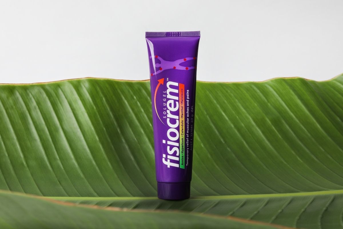 fisiocrem Solugel muscle pain relief cream tube standing upright on a large green leaf.